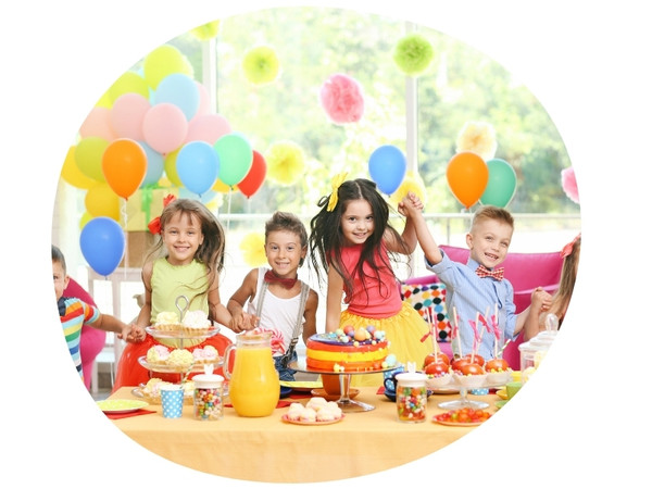 large group of children at a party table covered in sweets and surrounded by balloons